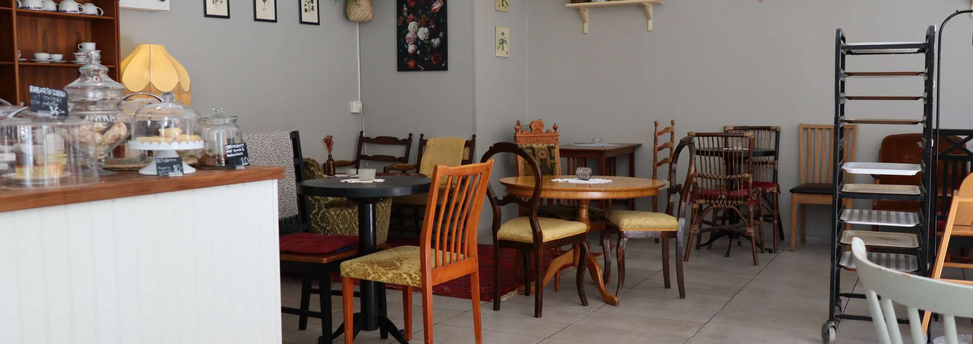 Insidan av ett café. Bord och stolar samt en bardisk syns