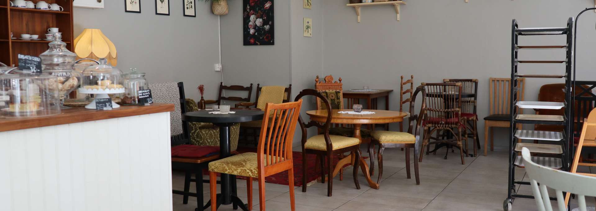 the interior of a small cafe with a counter, tables and chairs in an older style